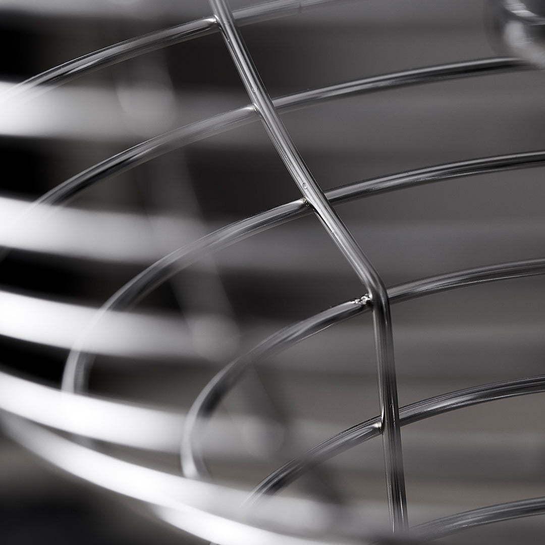 Close-up of shiny silver metal wire basket with smooth, curved lines and an intricate pattern. Perfect for modern decor.