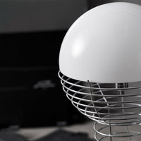 White dome-shaped lamp with a silver wire cage, set against a dark background. Elegant and modern design.