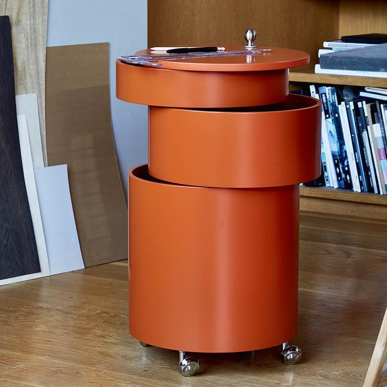Orange cylindrical storage unit with layered design and a glossy finish, perfect for modern interiors.