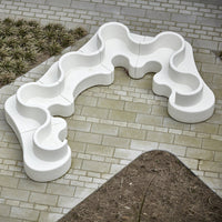 White ergonomic seating with flowing, wave-like patterns set on a textured stone surface. Ideal for modern outdoor spaces.