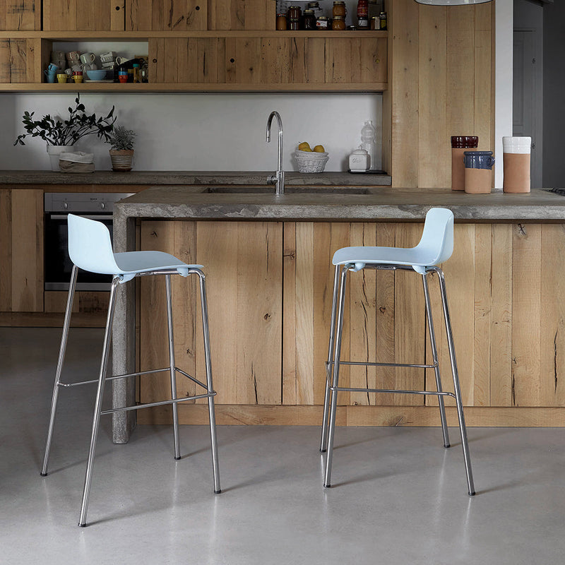 Blue bar stools with sleek chrome legs against a warm wood kitchen background. Modern, minimalist design.
