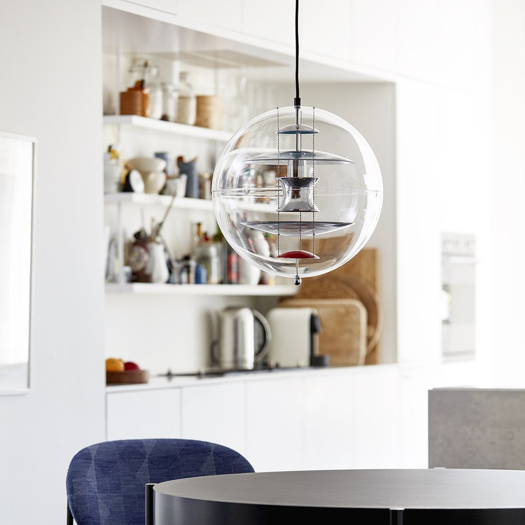 Clear glass pendant light with circular layers, complemented by a modern kitchen's neutral tones and blue accents.