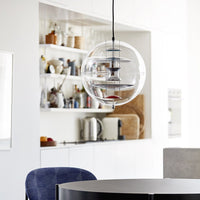 Clear glass pendant light with circular layers, complemented by a modern kitchen's neutral tones and blue accents.