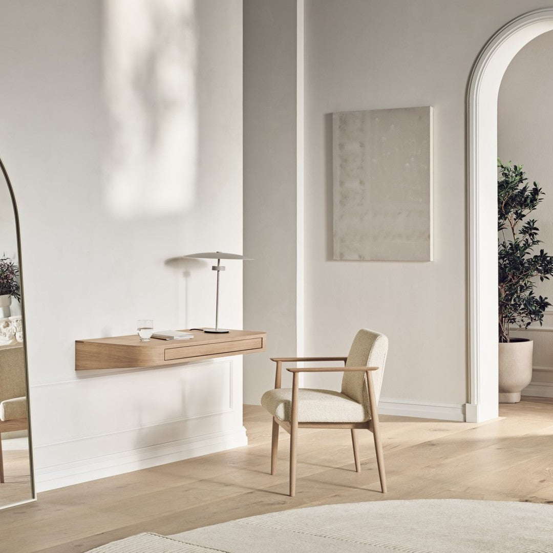 Minimalist beige chair against a light wood wall desk, featuring neutral tones and soft textures in a serene setting.