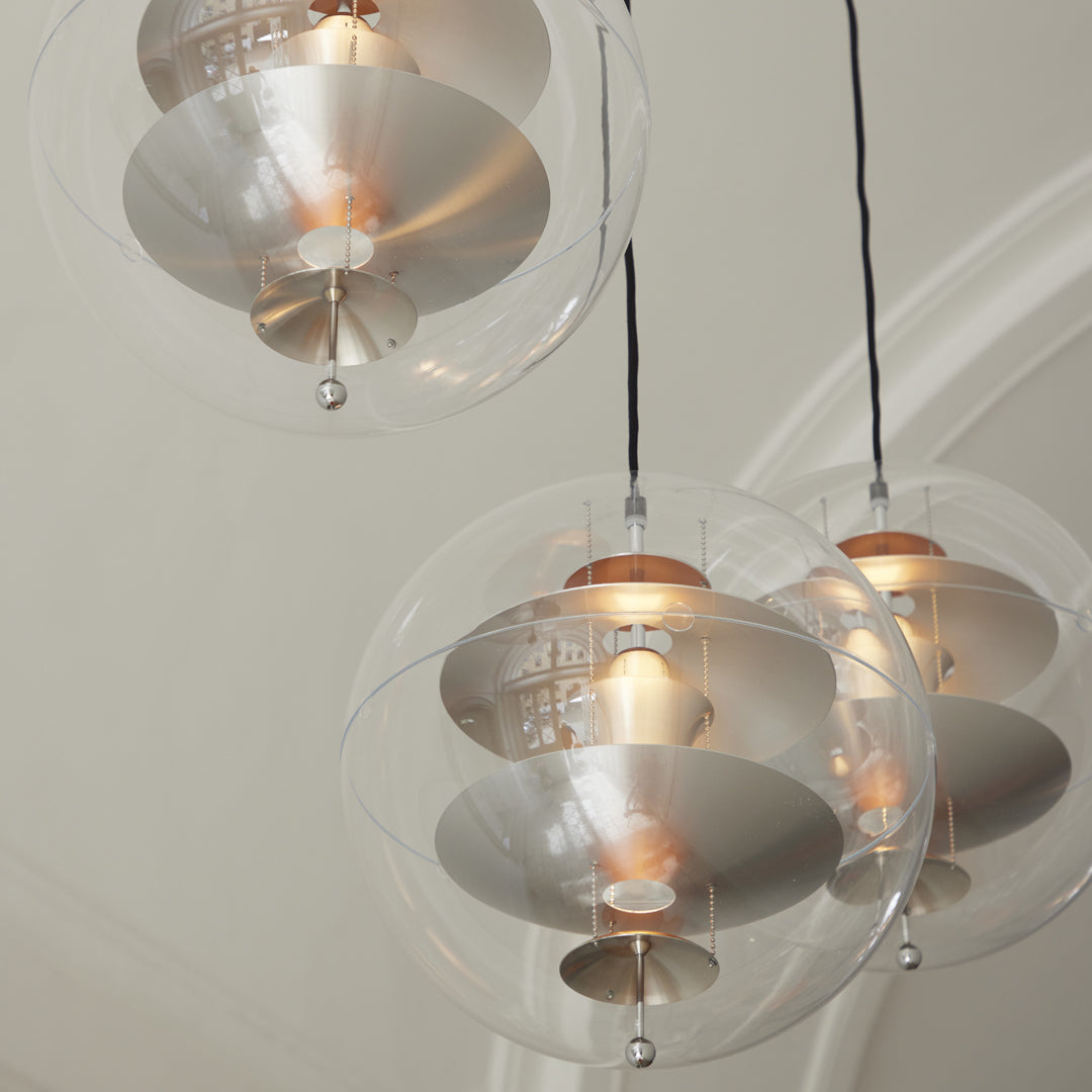 Clear glass pendant lights with silver shades and warm golden bulbs, creating a modern, sleek look.