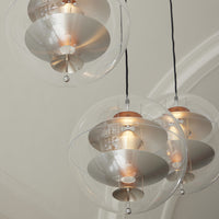 Clear glass pendant lights with silver shades and warm golden bulbs, creating a modern, sleek look.