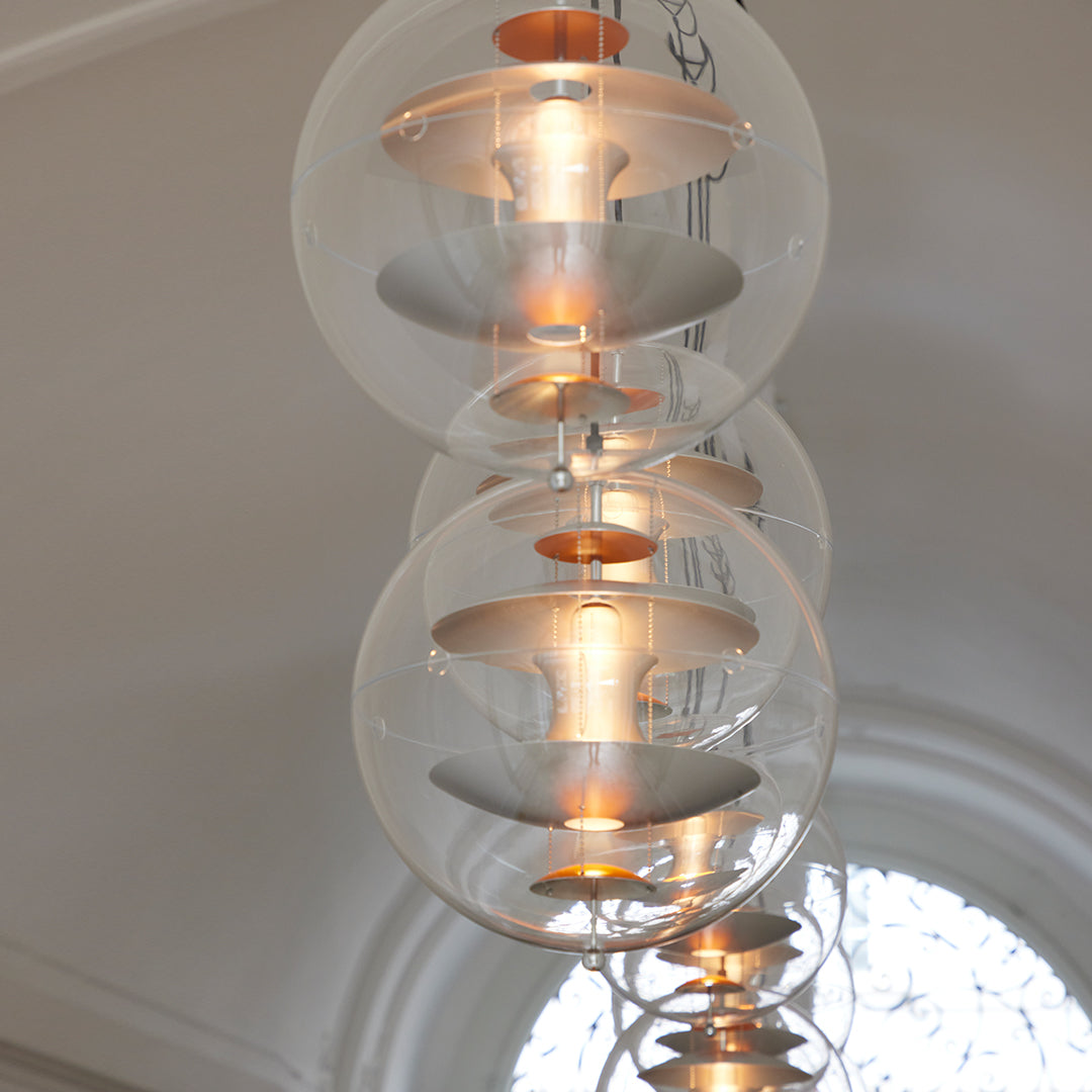 Clear glass pendant lights with metallic accents, featuring a sleek, modern design and vibrant warm glow.