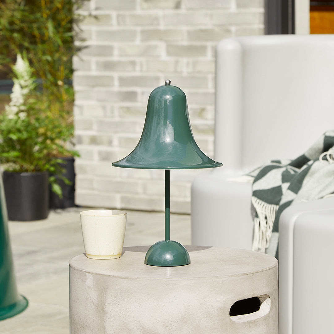 Green bell-shaped lamp on a minimalist gray table, surrounded by soothing neutral tones and patterns.