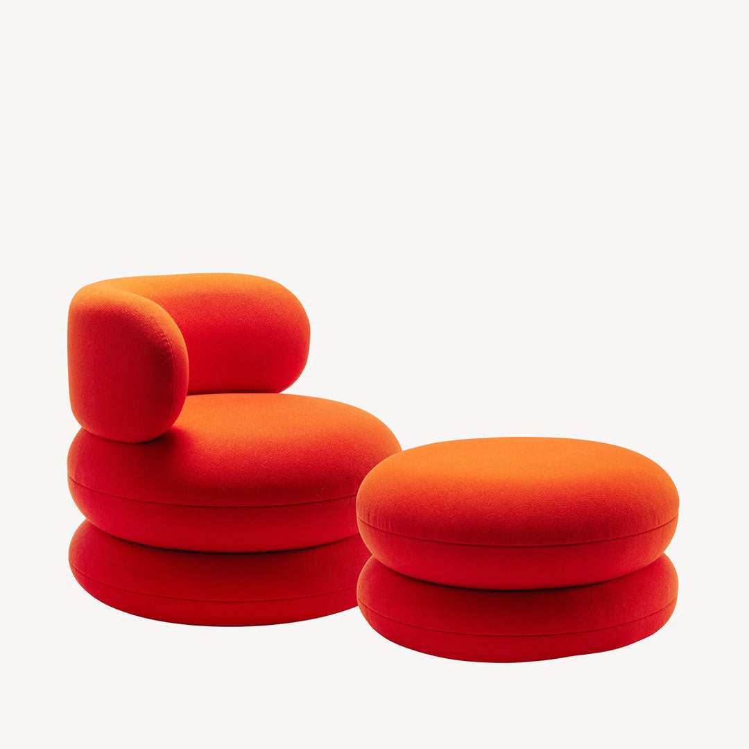 Vibrant red upholstered chair and ottoman set with smooth, rounded shapes and a plush texture. Perfect for modern decor.