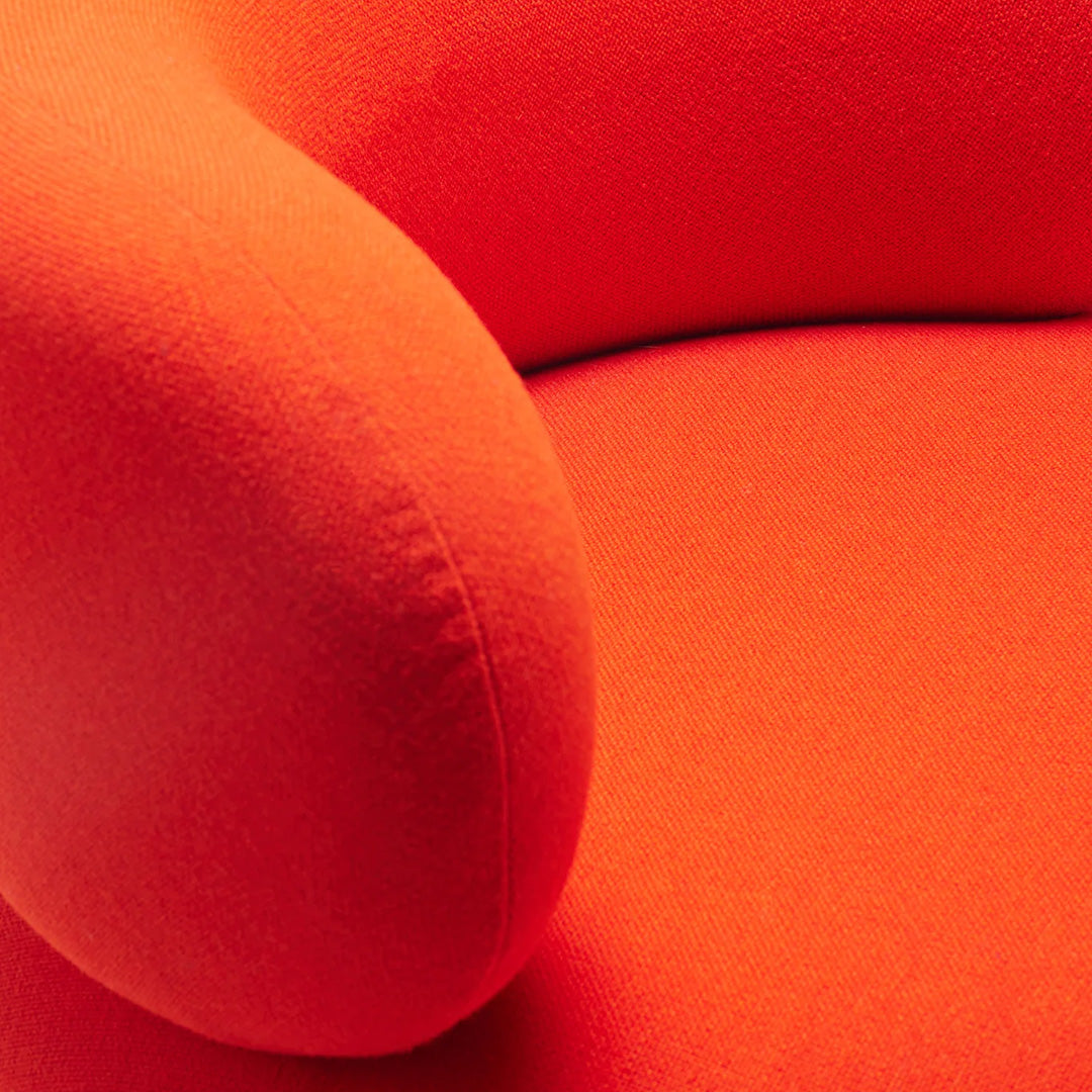 Vibrant orange textured fabric showcasing a smooth, rounded armrest and seat cushion. Perfect for modern decor.