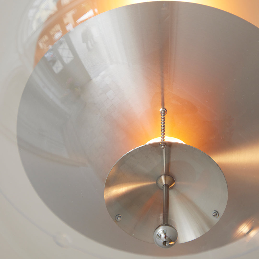 Sleek silver dome pendant light with a warm amber glow, featuring a modern, minimalist design.
