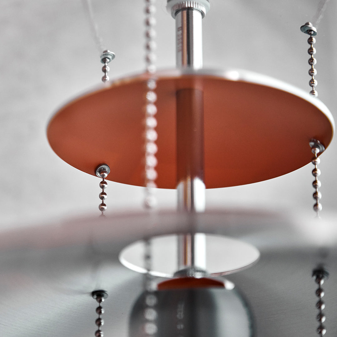 Copper and silver chandelier with circular shades and intricate bead detailing, showcasing a modern design.