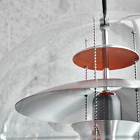 Modern chandelier with clear glass, silver accents, and copper circular layers, showcasing sleek contemporary design.