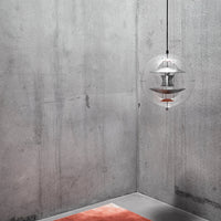 Modern interior featuring a transparent pendant light, gray concrete walls, and a soft orange rug.