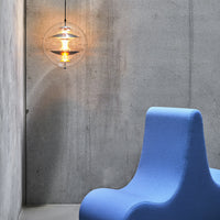 Modern blue chair beside a concrete wall, featuring a round glass pendant light with a warm glow.