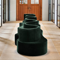 Curved green velvet seating with a soft texture, featuring deep emerald tones and a modern, sculptural design.