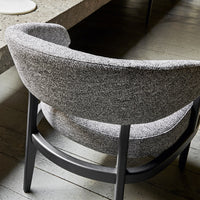Gray textured fabric armchair with a curved design and a sleek black wooden base. Modern aesthetic for stylish interiors.