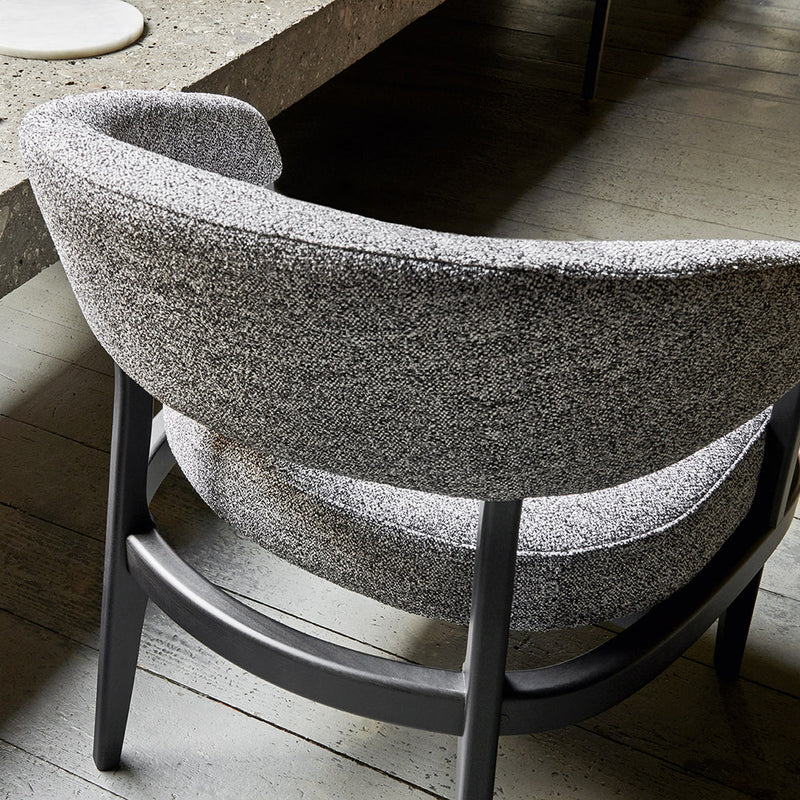 Gray textured fabric armchair with a curved design and a sleek black wooden base. Modern aesthetic for stylish interiors.