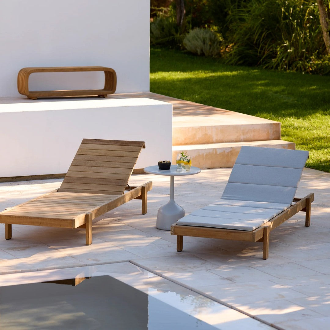 Wooden lounge chairs in natural brown and sleek gray, set against a clean white backdrop and green landscape.