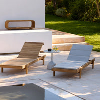 Wooden lounge chairs in natural brown and sleek gray, set against a clean white backdrop and green landscape.