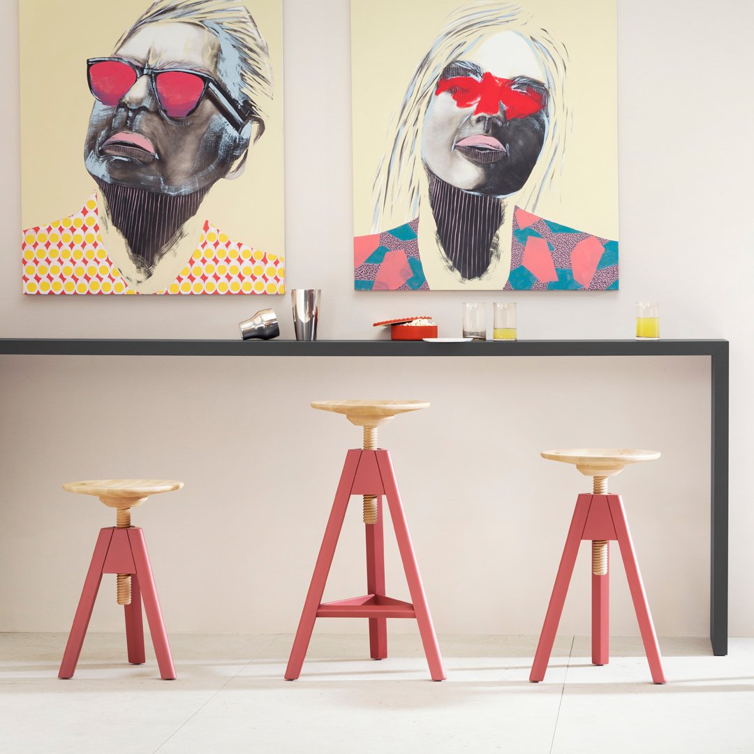 Red and natural wood bar stools with minimalist design, set against vibrant, abstract-patterned art.