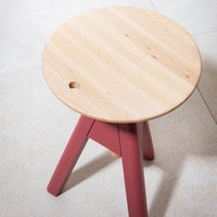 Natural wood top with subtle grain and round shape, featuring vibrant pink legs for a modern touch.