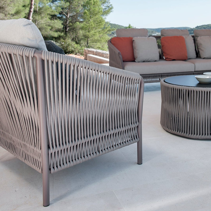"Light taupe outdoor chair with vertical woven pattern and coral-accented cushions on a modern patio."