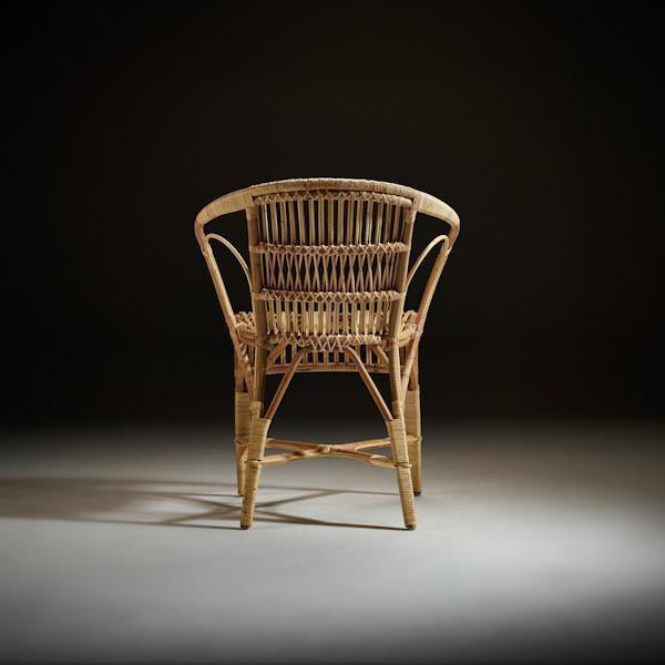 Natural rattan chair with intricate woven patterns, featuring a warm tan hue against a dark background.