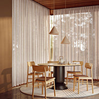 Sheer beige curtains with subtle texture, complemented by warm wood tones and soft, neutral circular rug.