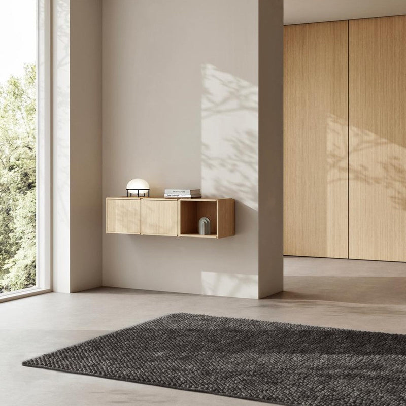 Modern interior featuring a light wood wall shelf, soft gray rug, and neutral walls, creating a calm, minimalist aesthetic.