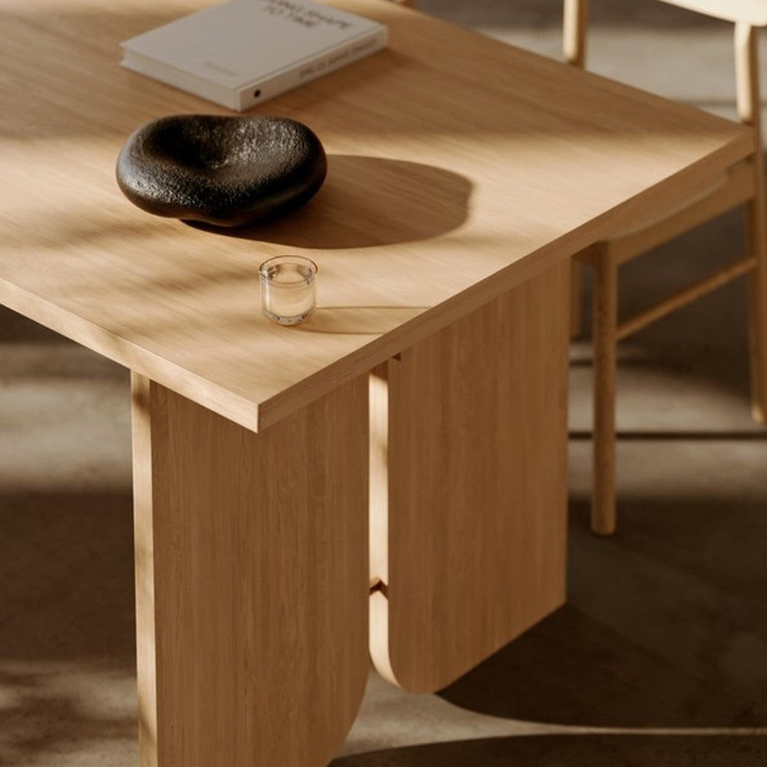 Light wooden table with a smooth finish, featuring a black stone and clear candle, set against a neutral background.