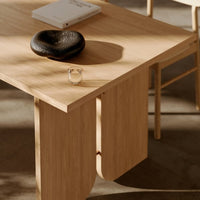 Light wooden table with a smooth finish, featuring a black stone and clear candle, set against a neutral background.