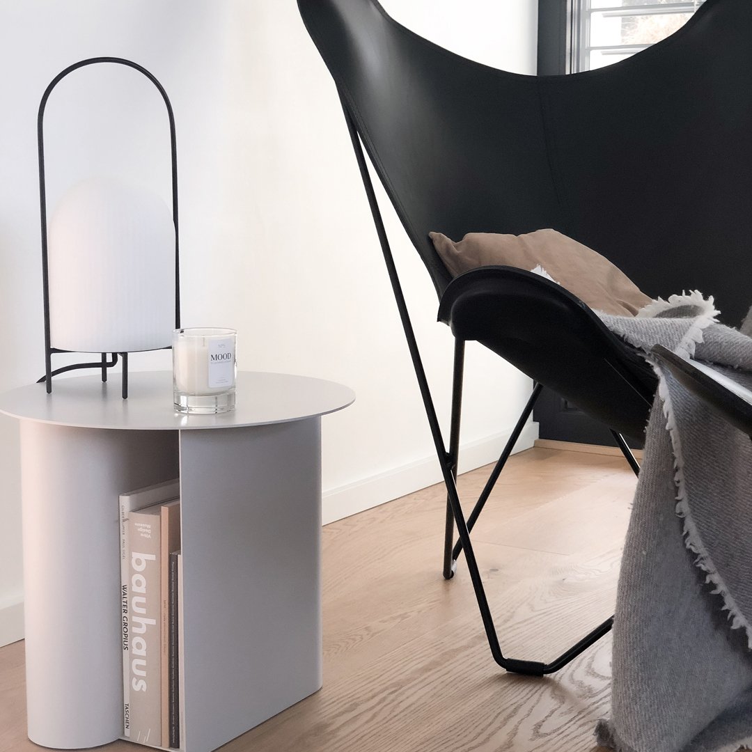Modern black chair, sleek white side table, warm beige throw, and neutral tones create a contemporary living space.