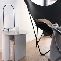 Modern black chair, sleek white side table, warm beige throw, and neutral tones create a contemporary living space.