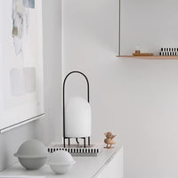 Minimalist decor featuring a white lamp with black accents, striped base, and grey bowls on a light background.