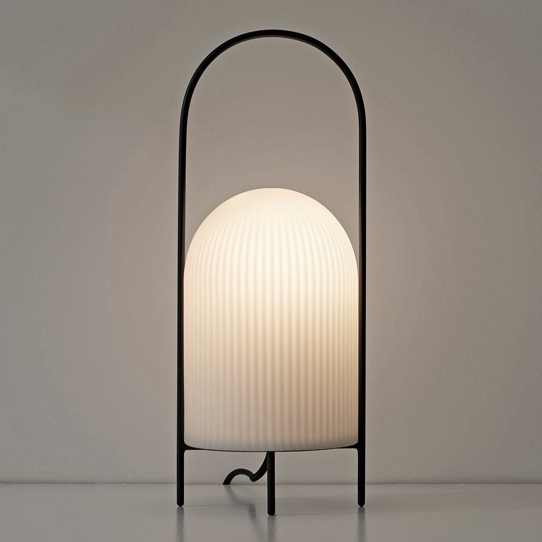 White ribbed glass lamp with a sleek black metal frame, featuring an elegant arch design.