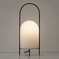 White ribbed glass lamp with a sleek black metal frame, featuring an elegant arch design.