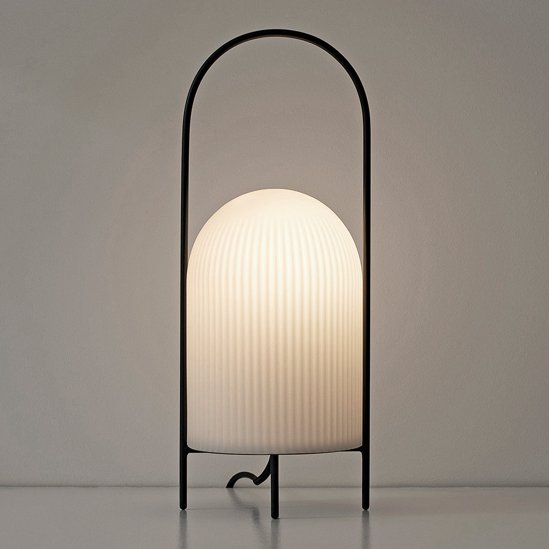 Black metal lamp with a ribbed white glass shade, creating a modern and minimalist aesthetic.