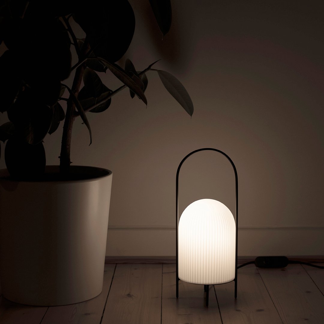 Elegant black arch lamp with a white pleated glass shade, set against a neutral background. Ideal for modern decor.