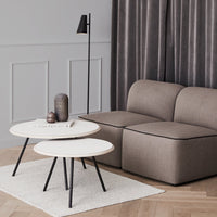 Modern coffee tables with white tops and black legs, complemented by a cozy beige sofa and gray curtains.