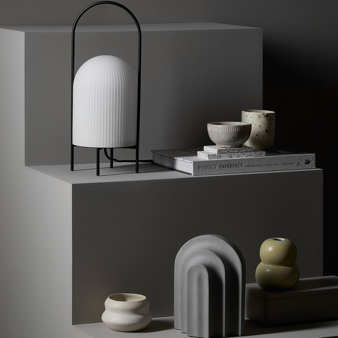 "Minimalist decor featuring white, gray, and earthy-toned vases on geometric display stands."