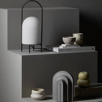 "Minimalist decor featuring white, gray, and earthy-toned vases on geometric display stands."