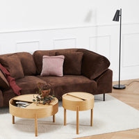 Brown suede couch with a pink accent pillow, paired with wooden tables on a neutral rug and light wood floor.