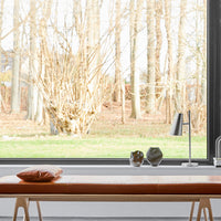Modern wooden bench with a warm brown cushion, featuring a sleek metal lamp and decorative glass accessories.