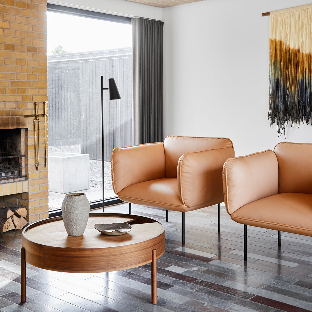Two stylish tan chairs with a round wooden table, featuring textured patterns in a modern living space.