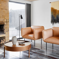 Two stylish tan chairs with a round wooden table, featuring textured patterns in a modern living space.