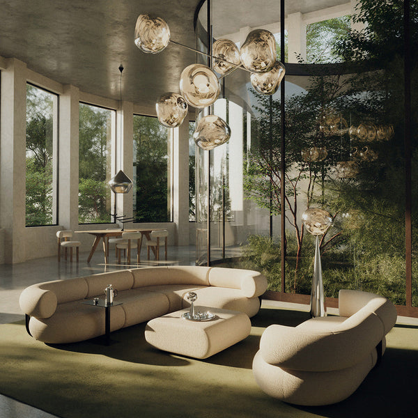 Beige curved sofa set with a soft green area rug, surrounded by natural greenery and modern light fixtures.