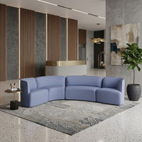 Curved blue sofa with a minimalist design, paired with a geometric patterned rug in neutral tones.