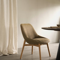 "Elegant beige upholstered chair with wooden legs, set against a soft cream backdrop and neutral tones."