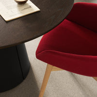 Red upholstered chair beside a dark wood table on a light-toned floor, creating a modern contrast.